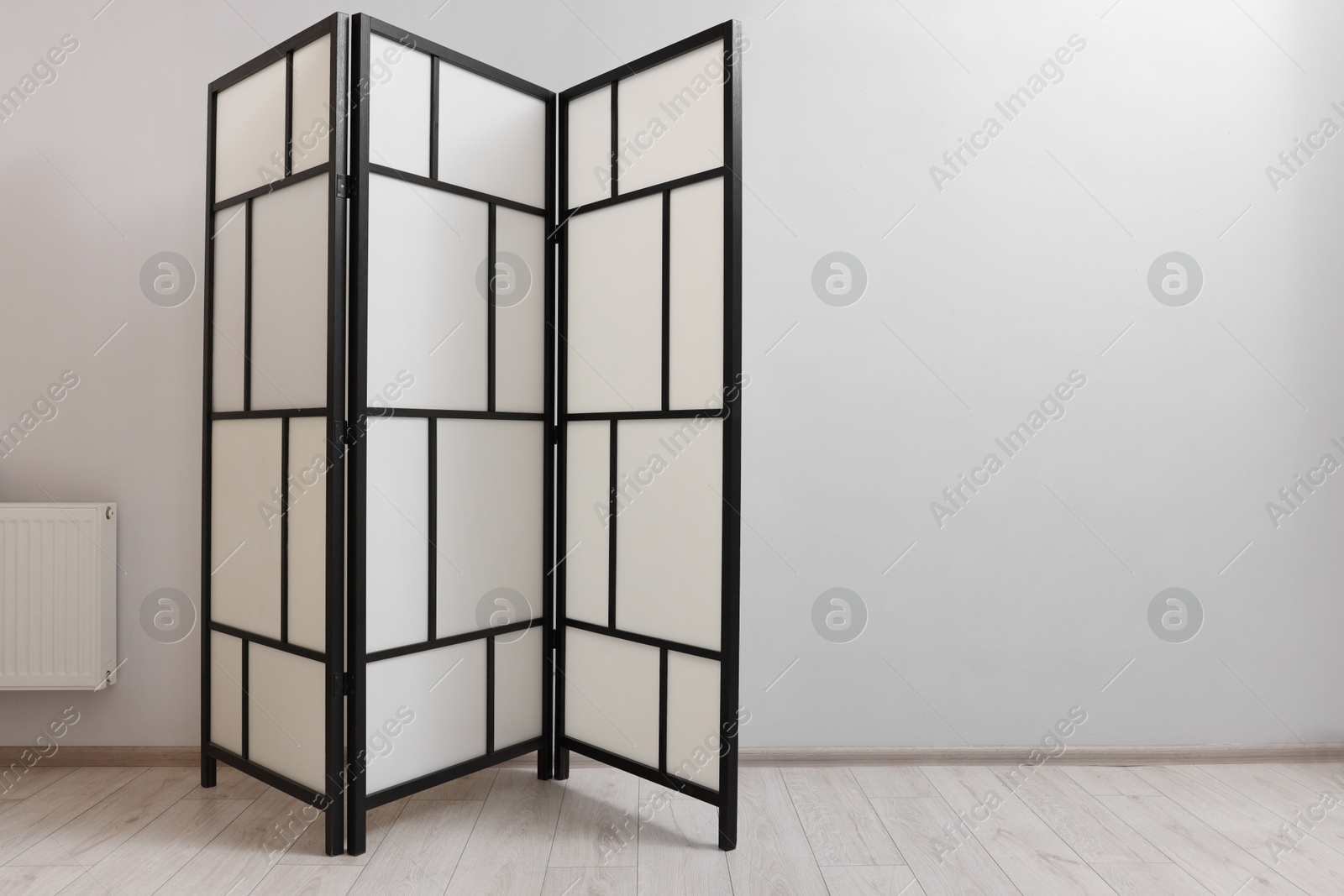 Photo of Folding screen near white wall indoors, space for text. Interior element