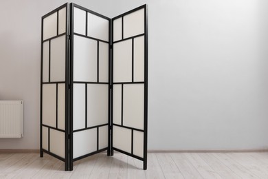 Photo of Folding screen near white wall indoors, space for text. Interior element