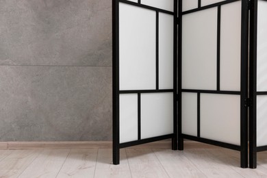 Photo of Stylish folding screen near grey wall indoors, space for text. Interior element