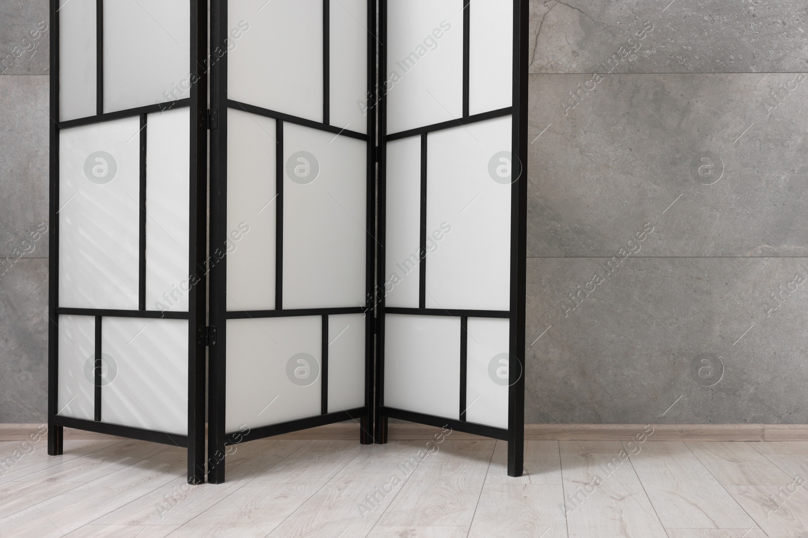 Photo of Stylish folding screen near grey wall indoors, space for text. Interior element