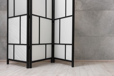 Photo of Stylish folding screen near grey wall indoors, space for text. Interior element