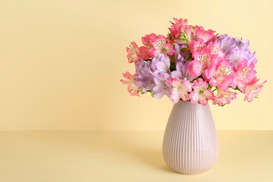 Photo of Beautiful alstroemeria flowers in vase on beige background, space for text