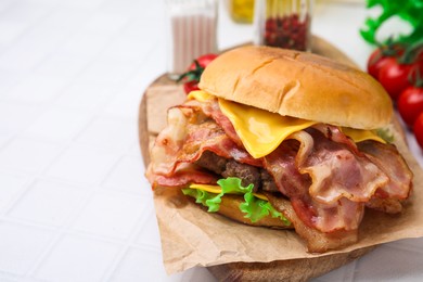 Delicious burger with bacon, patty and cheese on white table, space for text