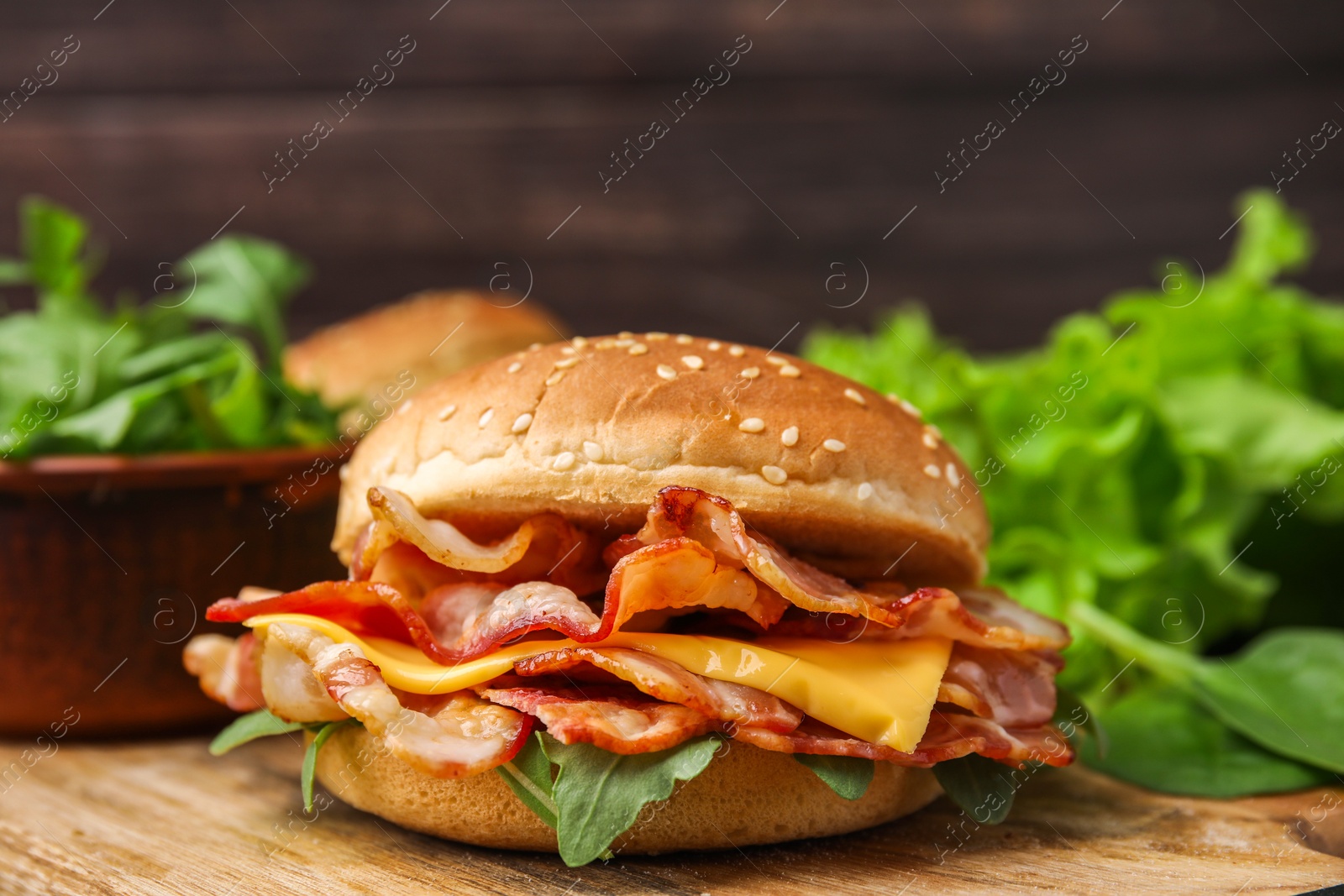 Photo of Delicious burger with bacon and cheese on table