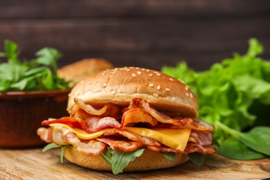 Photo of Delicious burger with bacon and cheese on table