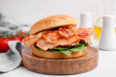 Delicious burger with bacon and greens on light table, closeup