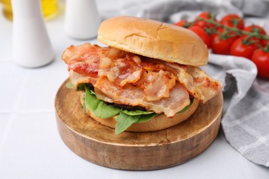 Delicious burger with bacon and greens on light table, closeup