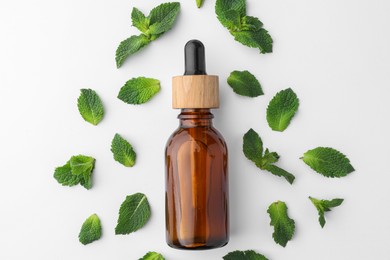 Photo of Bottle of essential oil and mint isolated on white, top view