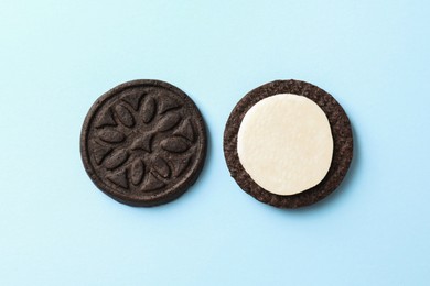 Photo of Halves of tasty sandwich cookie on light blue background, top view