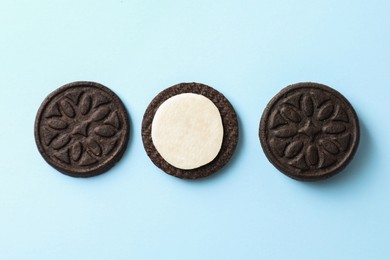 Photo of Tasty sandwich cookies with cream on light blue background, top view