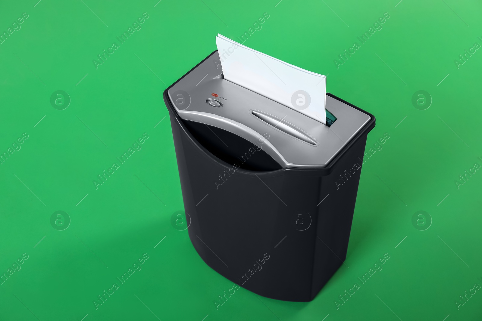 Photo of Shredder with sheet of paper on green background