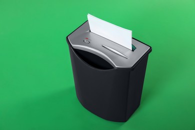 Photo of Shredder with sheet of paper on green background