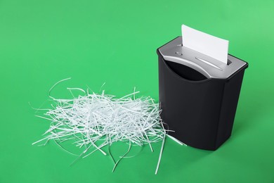 Photo of Shredder and pile of paper strips on green background