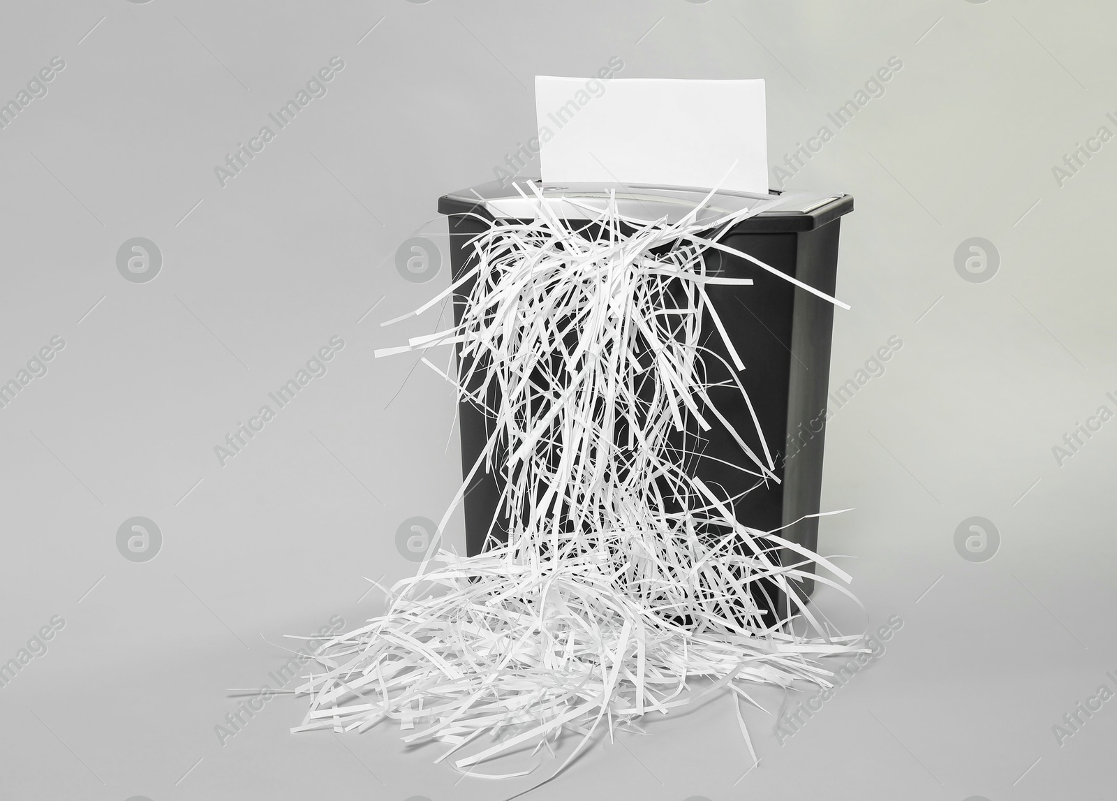 Photo of Destroying sheet of paper with shredder on light grey background, space for text