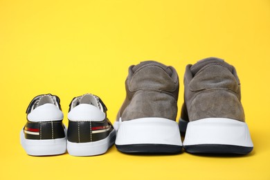 Photo of Big and small shoes on yellow background