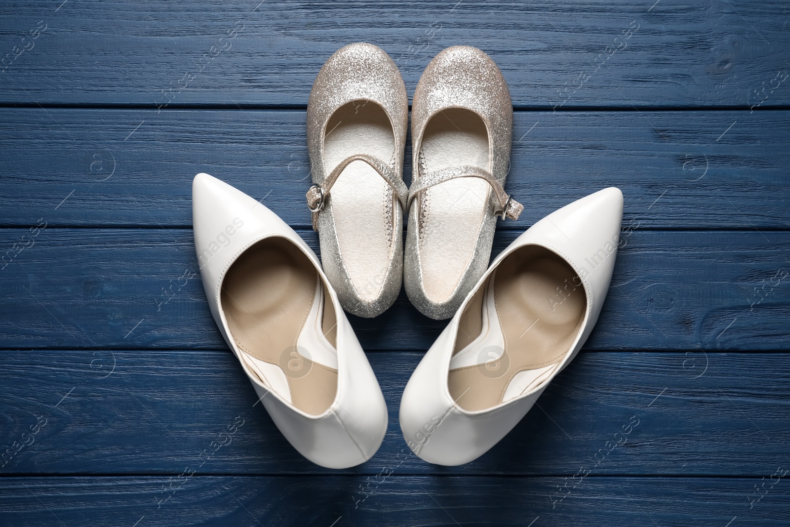 Photo of Big and small shoes on blue wooden table, top view