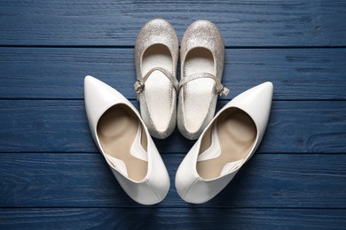 Big and small shoes on blue wooden table, top view