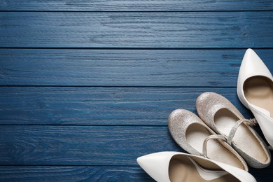 Big and small shoes on blue wooden table, top view. Space for text