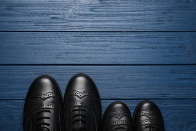 Photo of Big and small shoes on blue wooden table, top view. Space for text