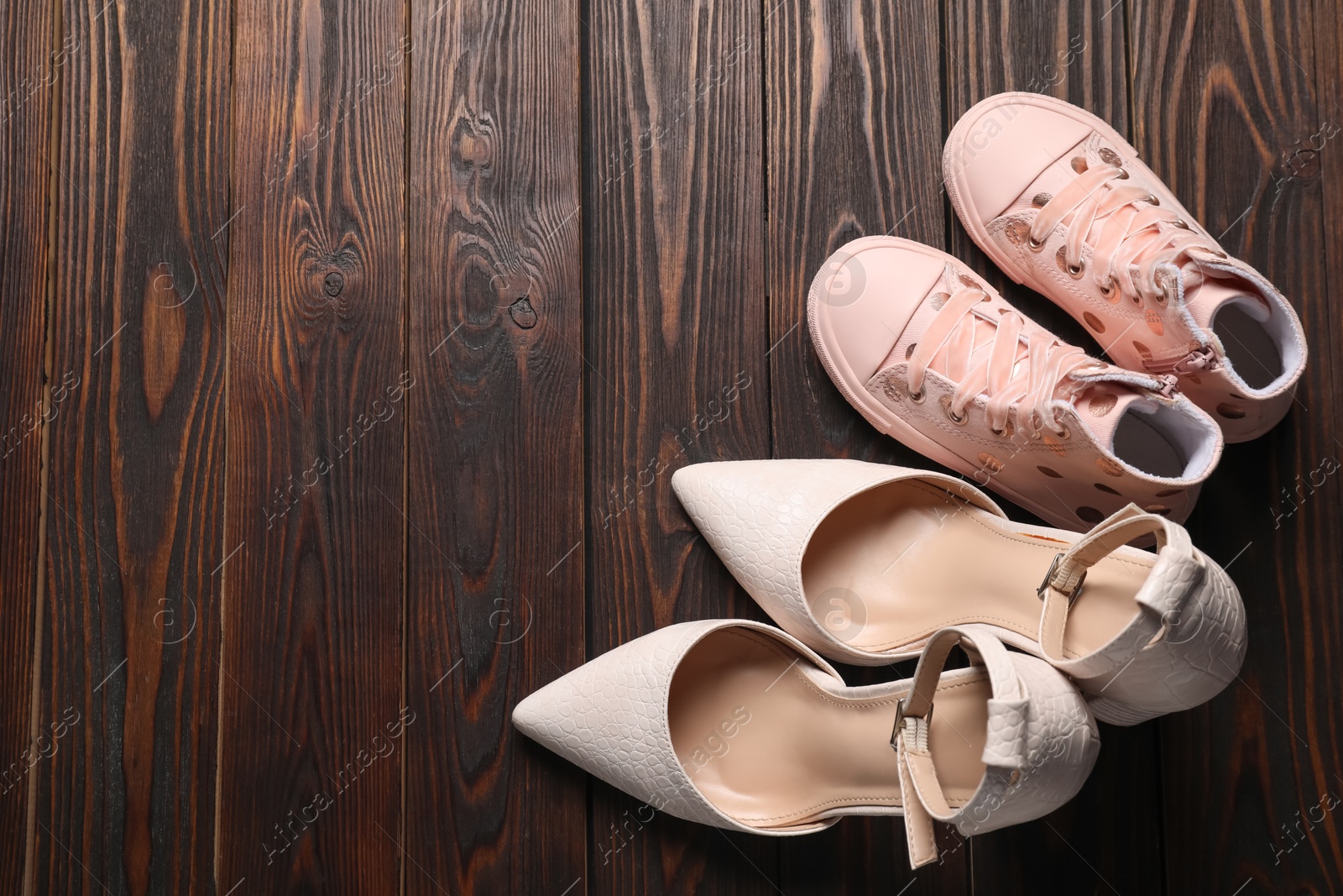 Photo of Big and small shoes on wooden table, top view. Space for text