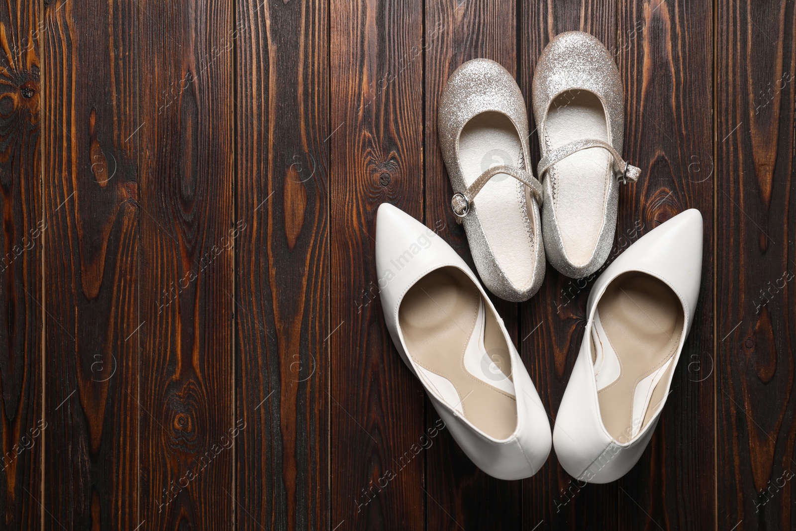 Photo of Big and small shoes on wooden table, top view. Space for text