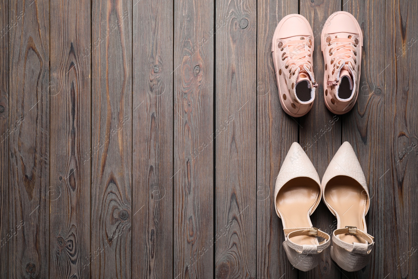 Photo of Big and small shoes on wooden table, top view. Space for text