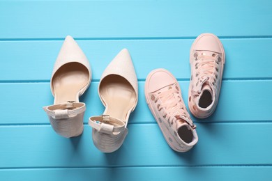 Photo of Big and small shoes on light blue wooden table, top view