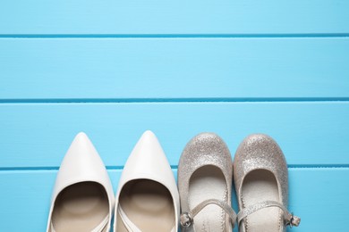 Photo of Big and small shoes on light blue wooden table, top view. Space for text