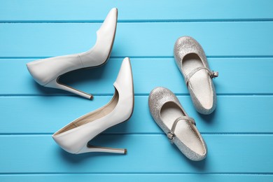 Photo of Big and small shoes on light blue wooden table, flat lay