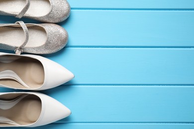 Photo of Big and small shoes on light blue wooden table, top view. Space for text