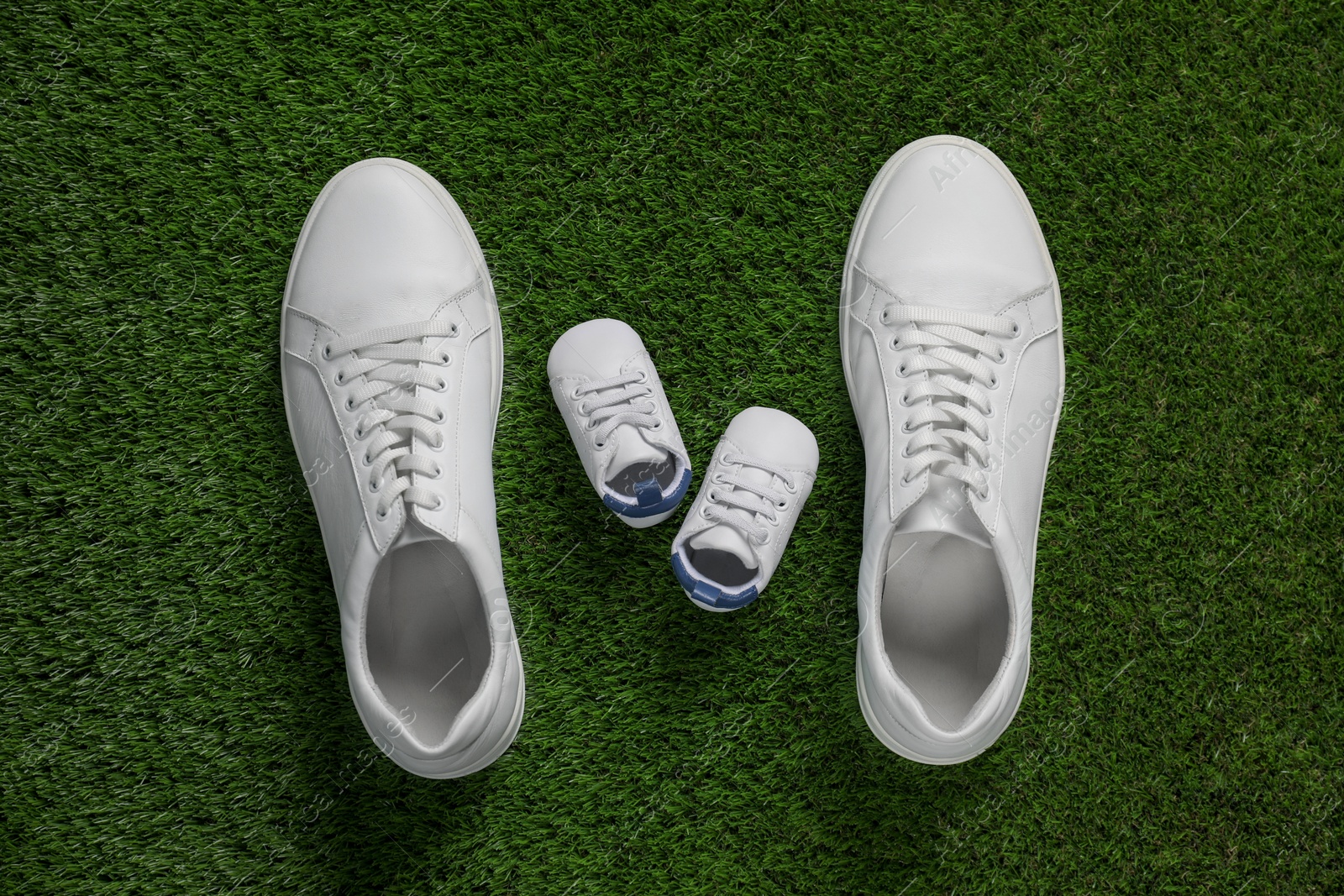 Photo of Big and small shoes on green grass, top view