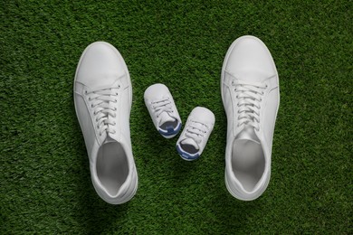 Big and small shoes on green grass, top view