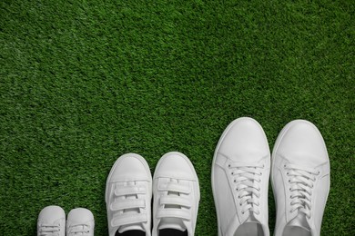 Photo of Big and small shoes on green grass, top view. Space for text