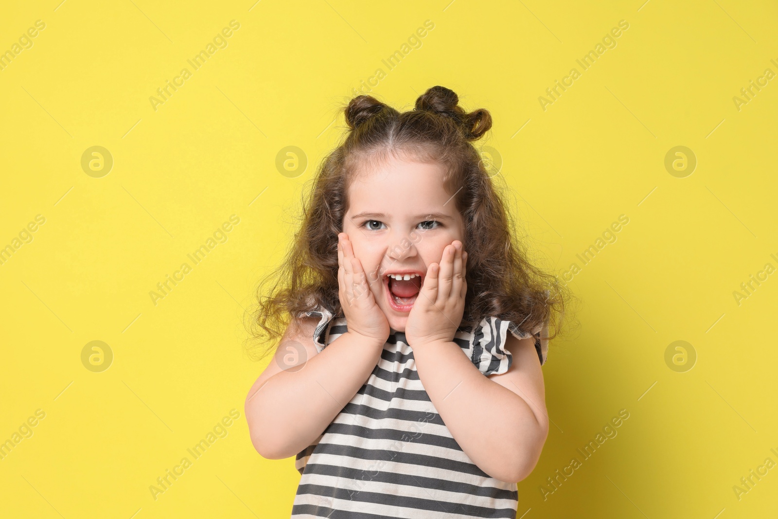 Photo of Portrait of happy girl on yellow background. Adorable child