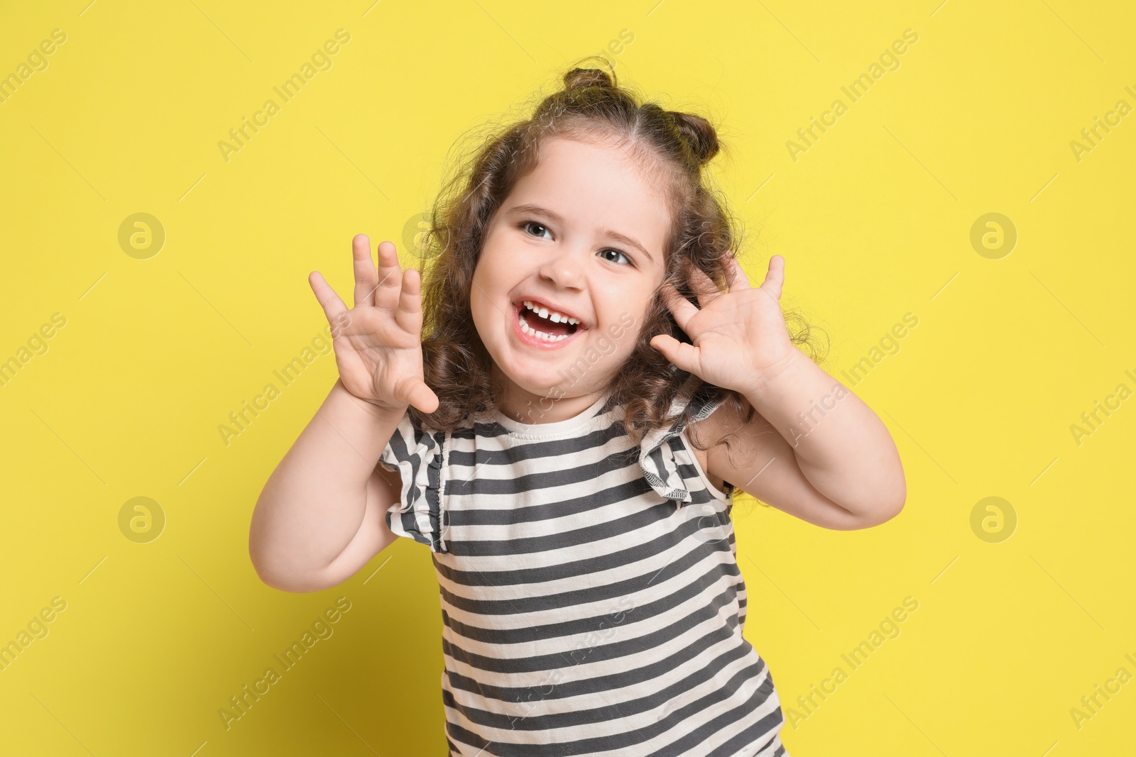 Photo of Portrait of happy girl on yellow background. Adorable child