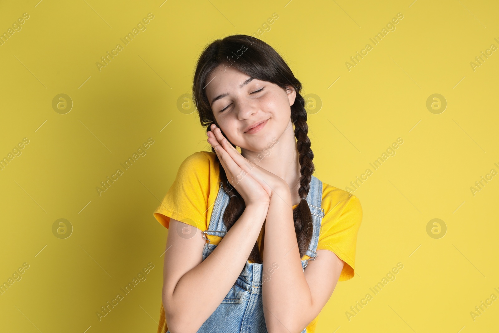 Photo of Portrait of cute teenage girl on yellow background