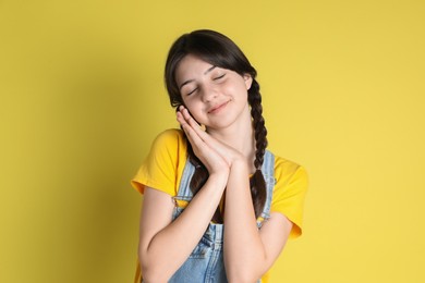 Portrait of cute teenage girl on yellow background