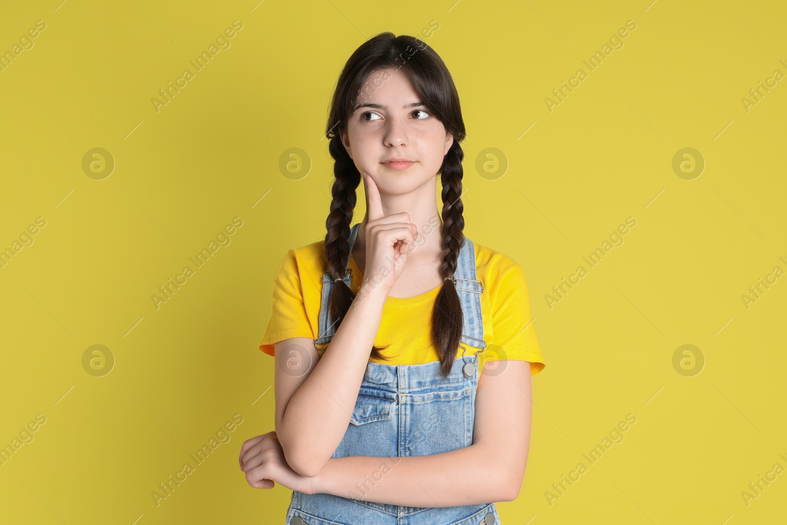 Photo of Portrait of cute teenage girl on yellow background