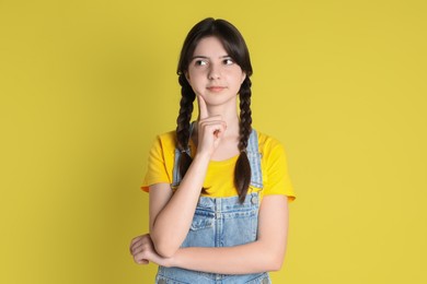 Portrait of cute teenage girl on yellow background