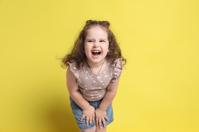 Photo of Portrait of little girl on yellow background. Emotional child