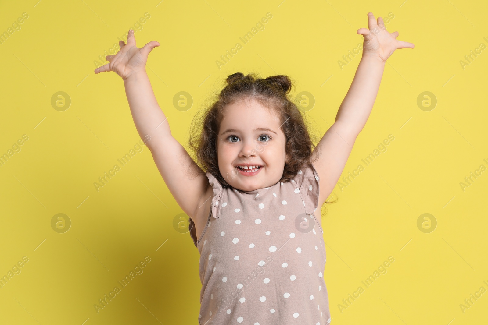 Photo of Portrait of happy girl on yellow background. Adorable child