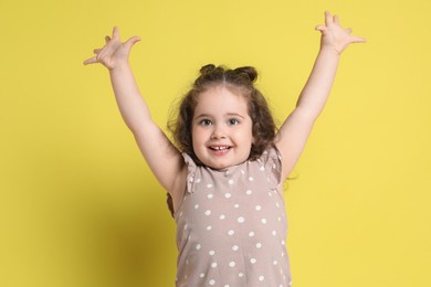 Photo of Portrait of happy girl on yellow background. Adorable child