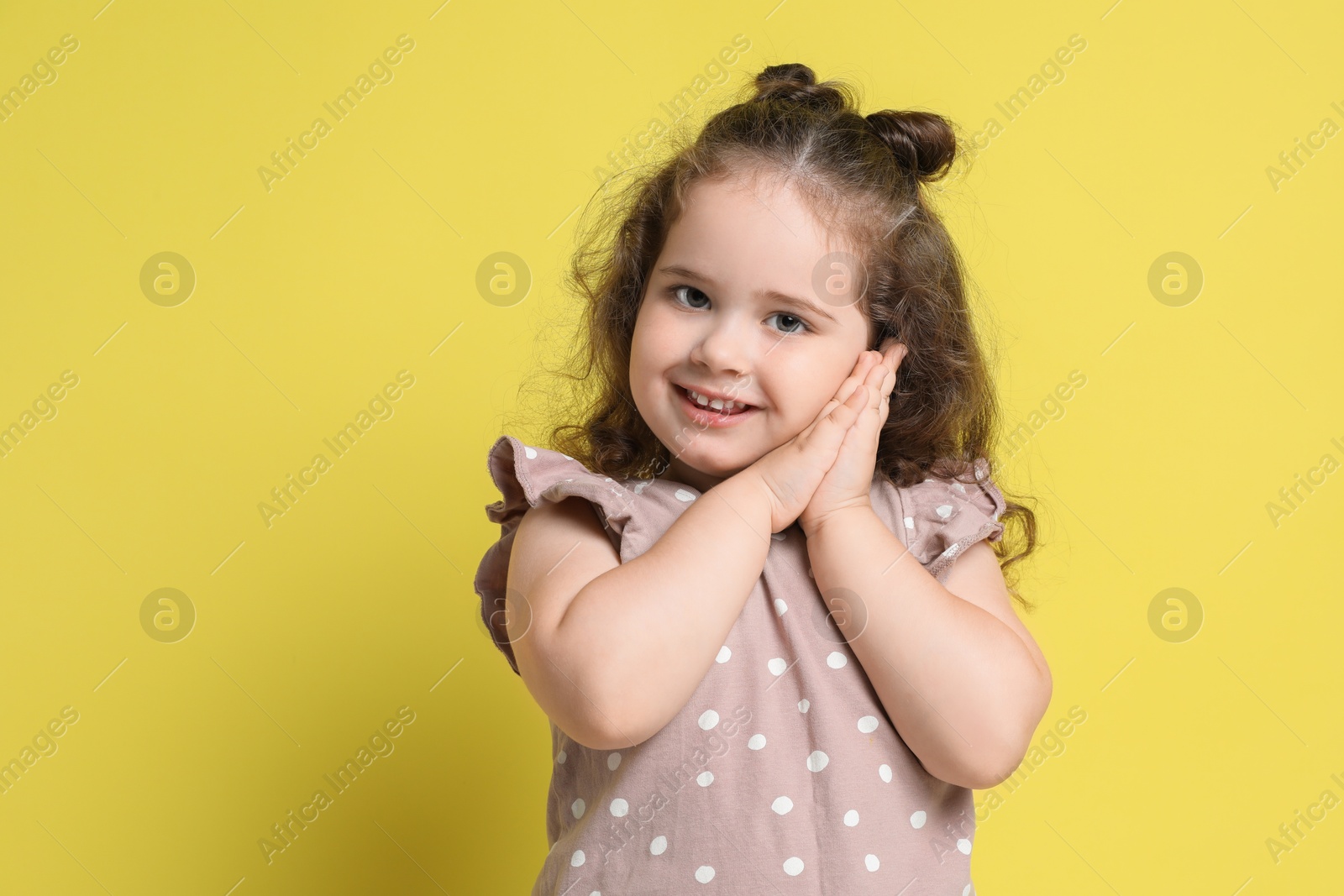 Photo of Portrait of smiling girl on yellow background, space for text. Adorable child