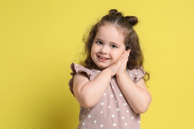 Photo of Portrait of smiling girl on yellow background, space for text. Adorable child