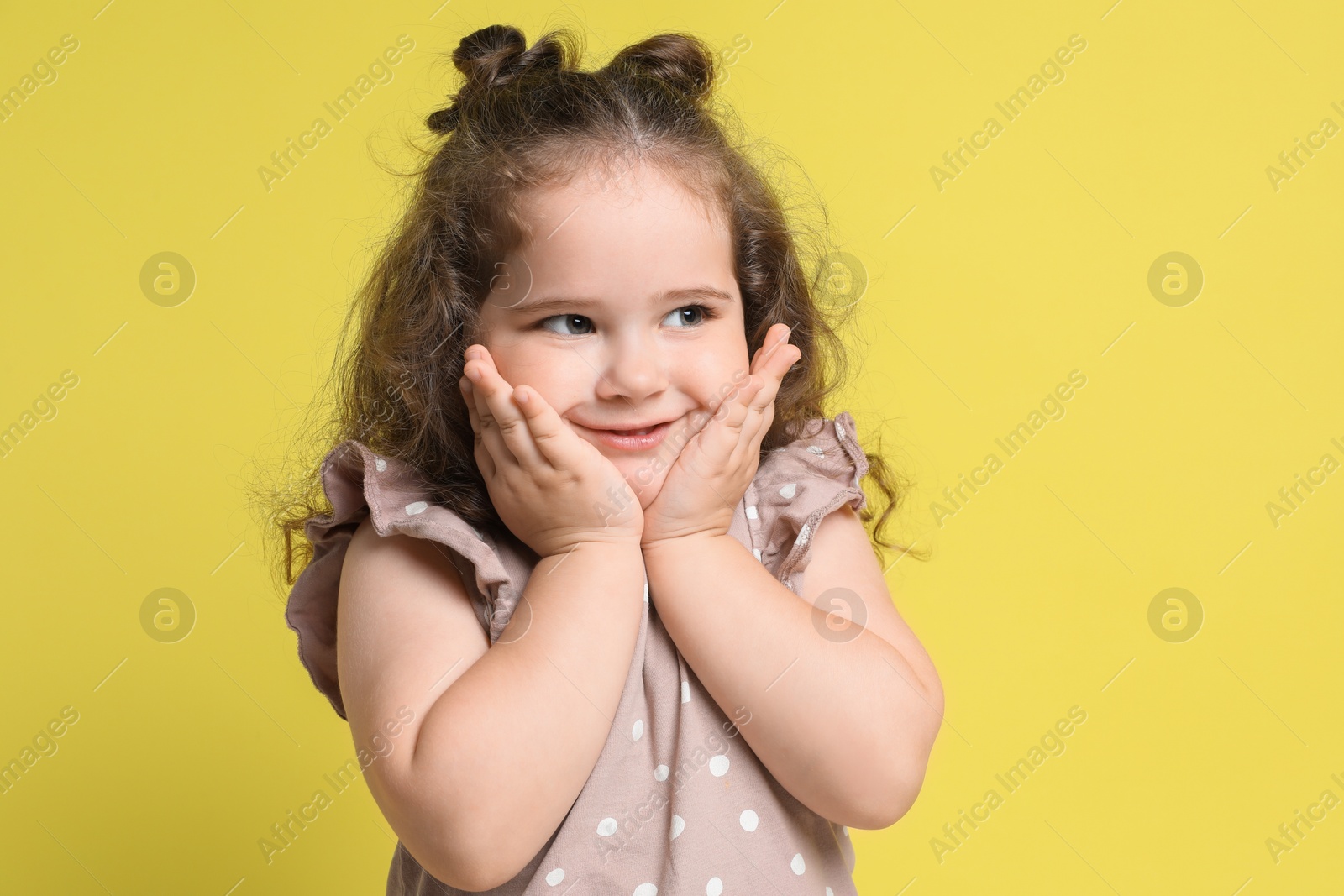 Photo of Portrait of cute girl on yellow background. Adorable child