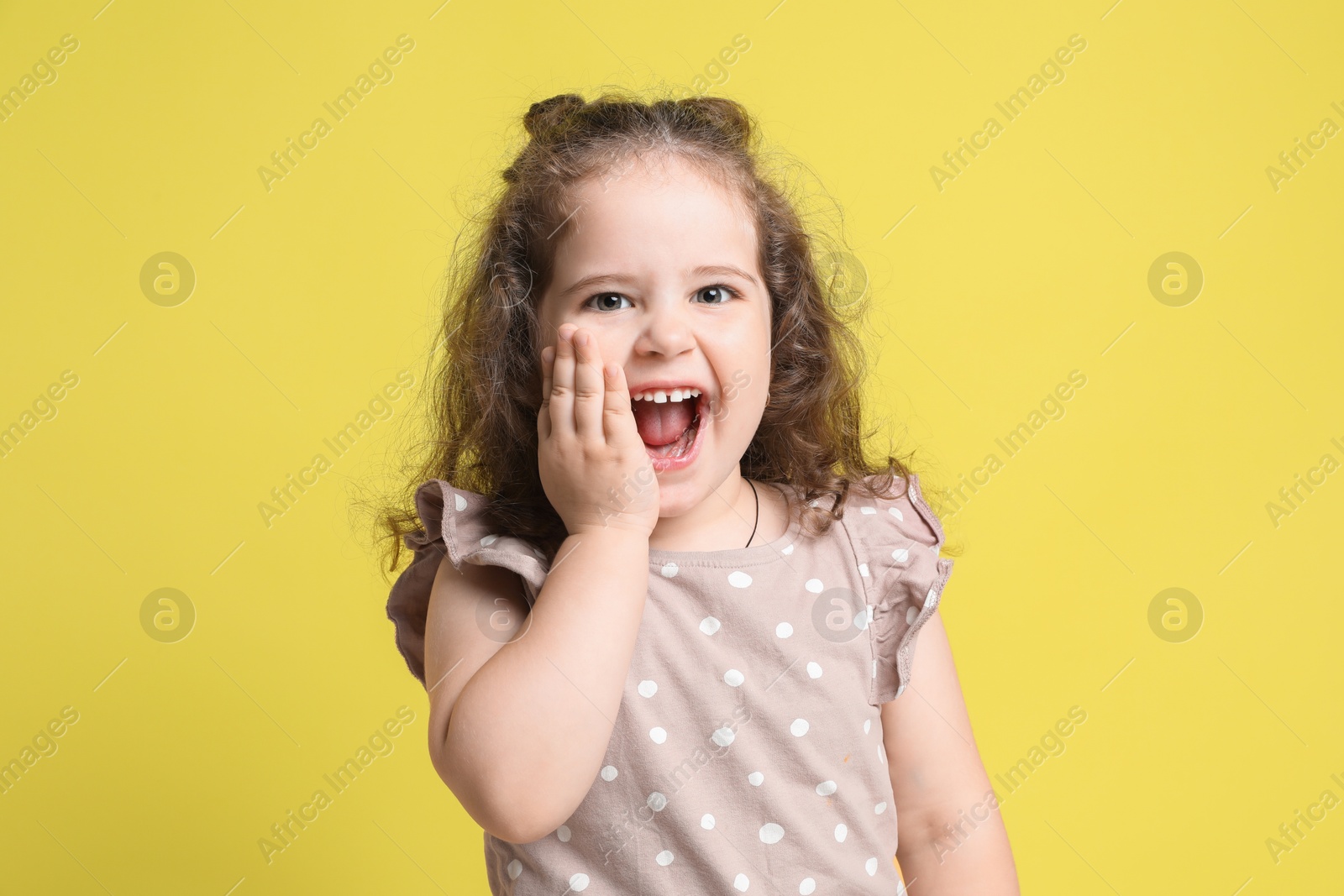 Photo of Portrait of cute girl on yellow background. Emotional child