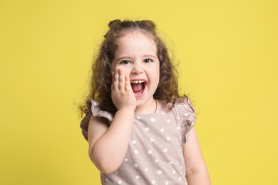 Portrait of cute girl on yellow background. Emotional child