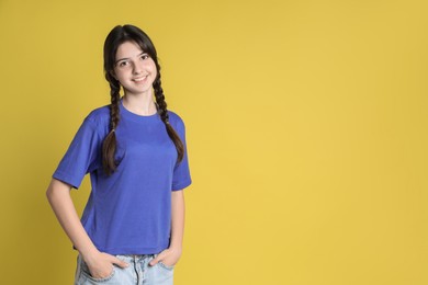 Photo of Portrait of smiling teenage girl on yellow background. Space for text