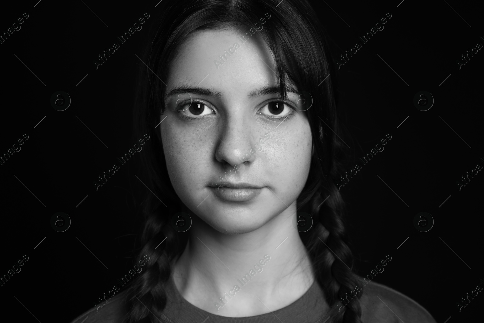 Photo of Portrait of teenage girl on dark background. Black and white effect