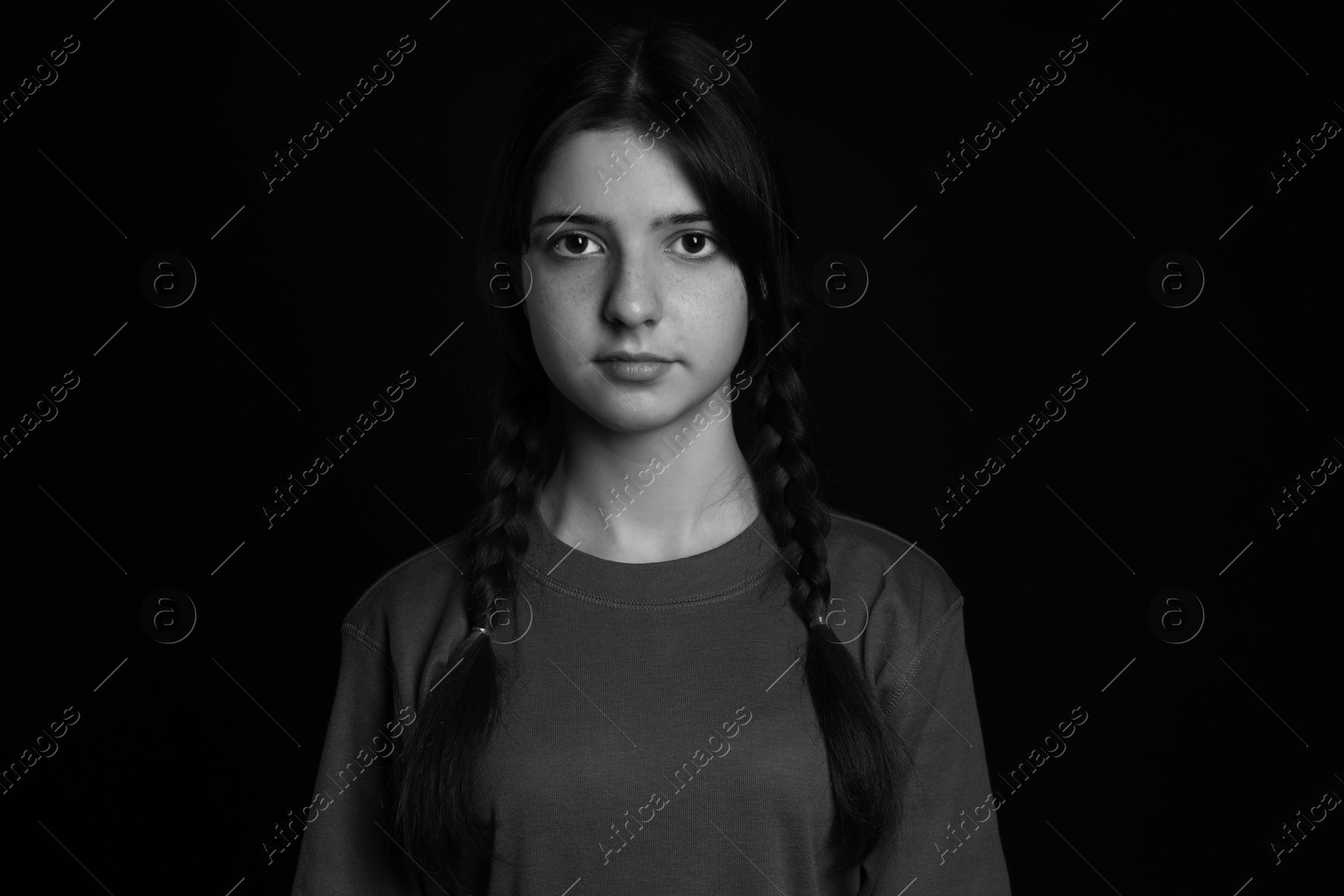 Photo of Portrait of teenage girl on dark background. Black and white effect